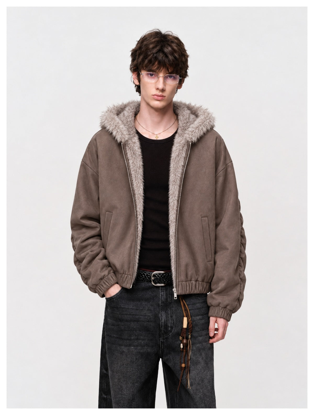 Man wearing a taupe zip-front jacket with a pale faux-fur hood and trim, shown with a black shirt and dark jeans.
