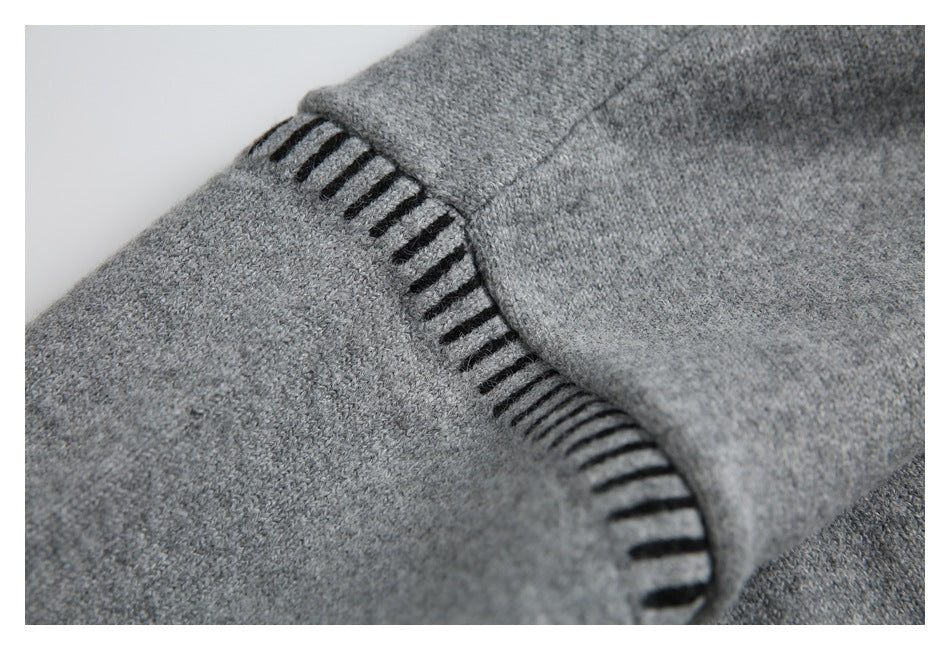 Gray knit sweater seam detail with black decorative stitch accents.