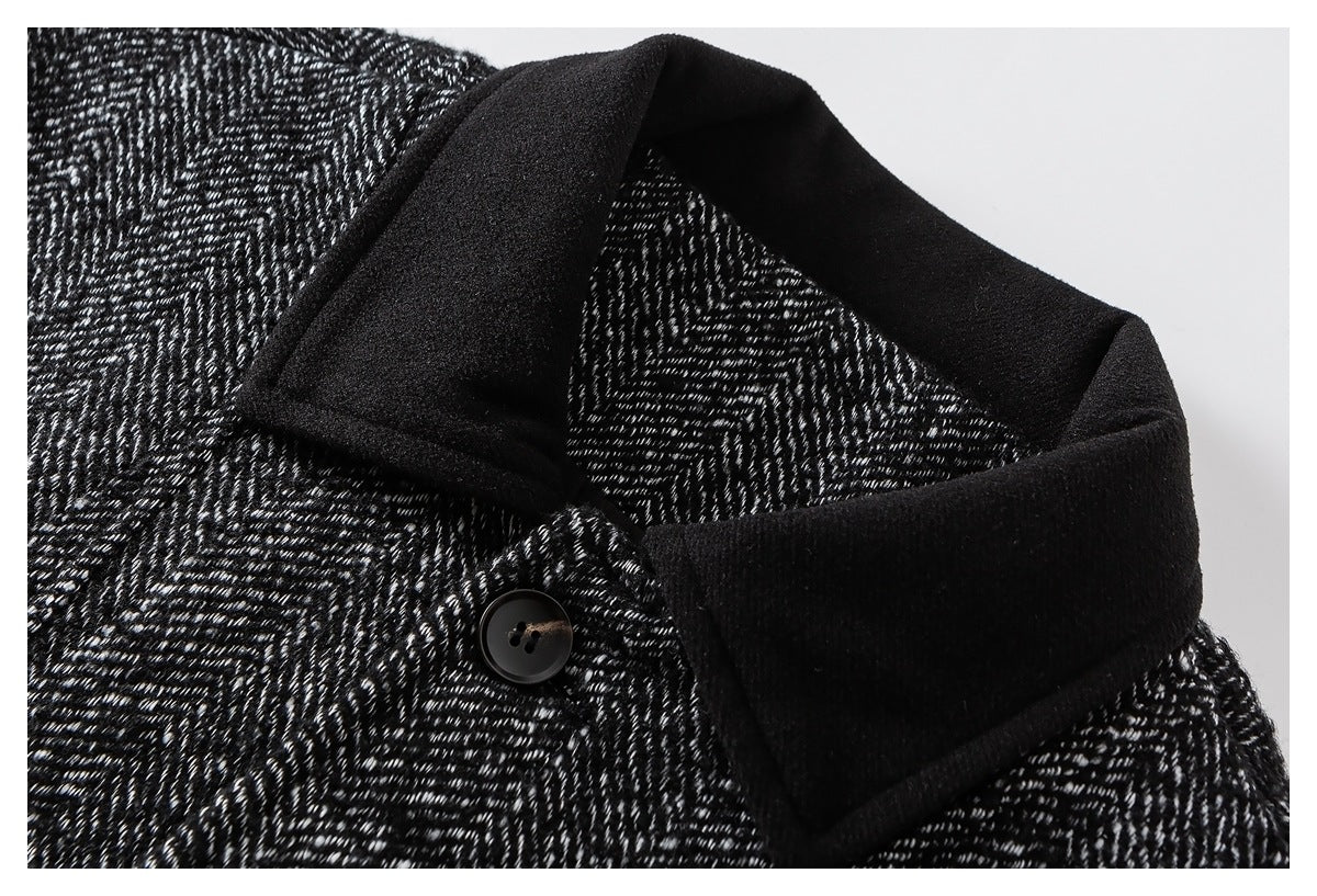 Close-up of a black collar and button on a black-and-white herringbone jacket.