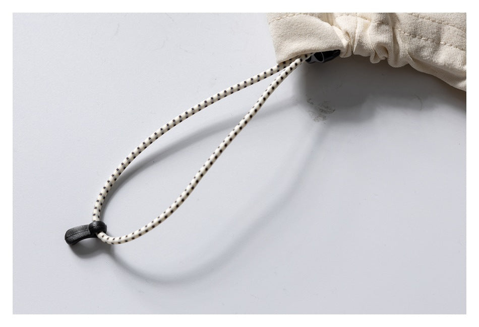 Close-up of the cream sweatshirt’s dotted drawcord and black cord lock.