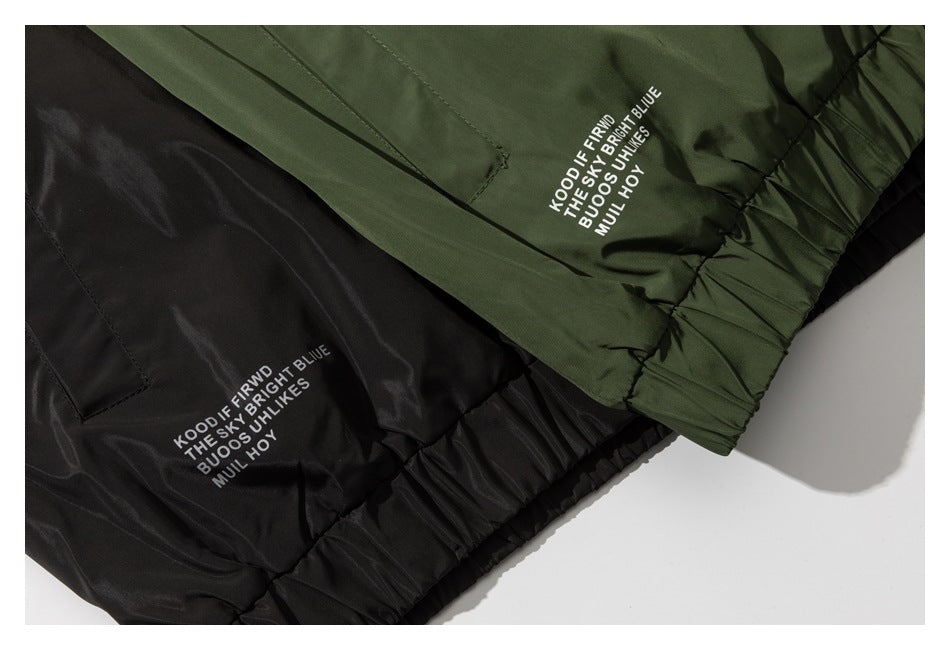 Close-up of black and olive garments with gathered elastic hems and white text printed on the fabric.