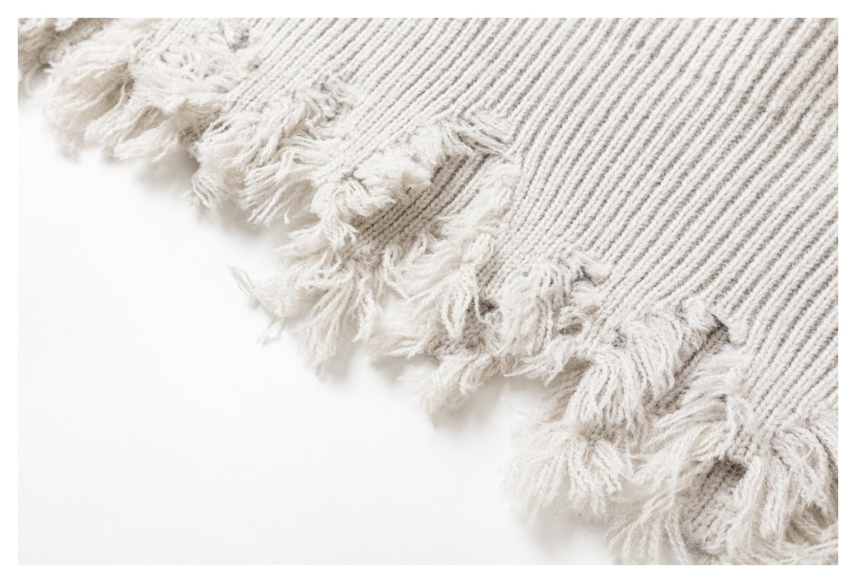 Close-up of an ivory rib-knit edge finished with loose fringe.