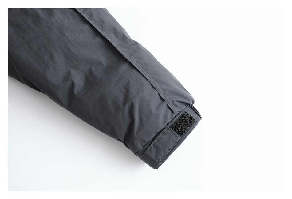 Close-up of a charcoal-gray sleeve ending in an adjustable cuff with a black hook-and-loop tab.