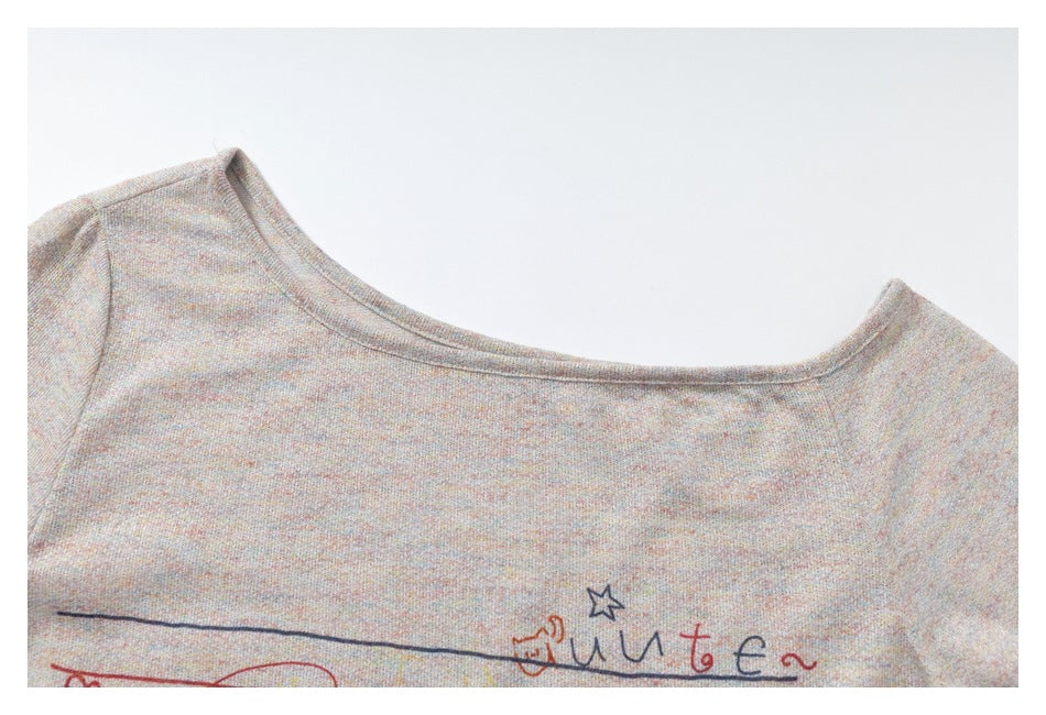 Close-up of a wide neckline on a light gray speckled top, with part of a colorful line-art print visible.