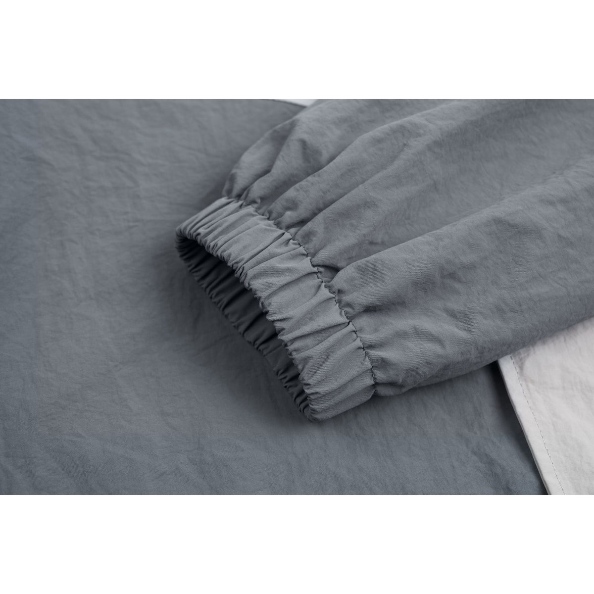 Close-up of the gray jacket's gathered elastic cuff and sleeve seam.