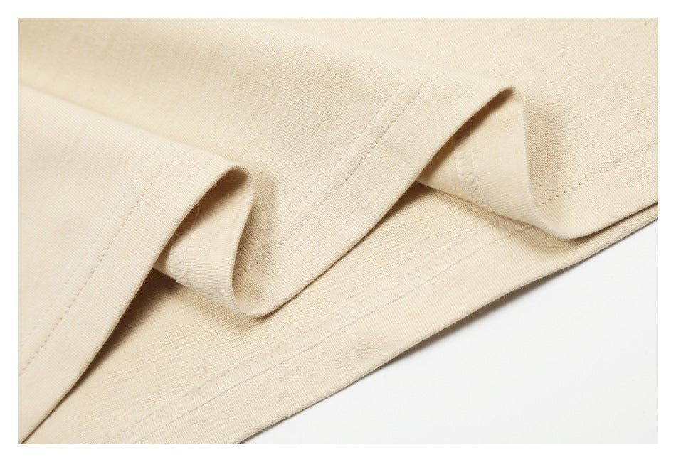 Close-up of a light beige garment hem folded to show its stitching and inner edge.
