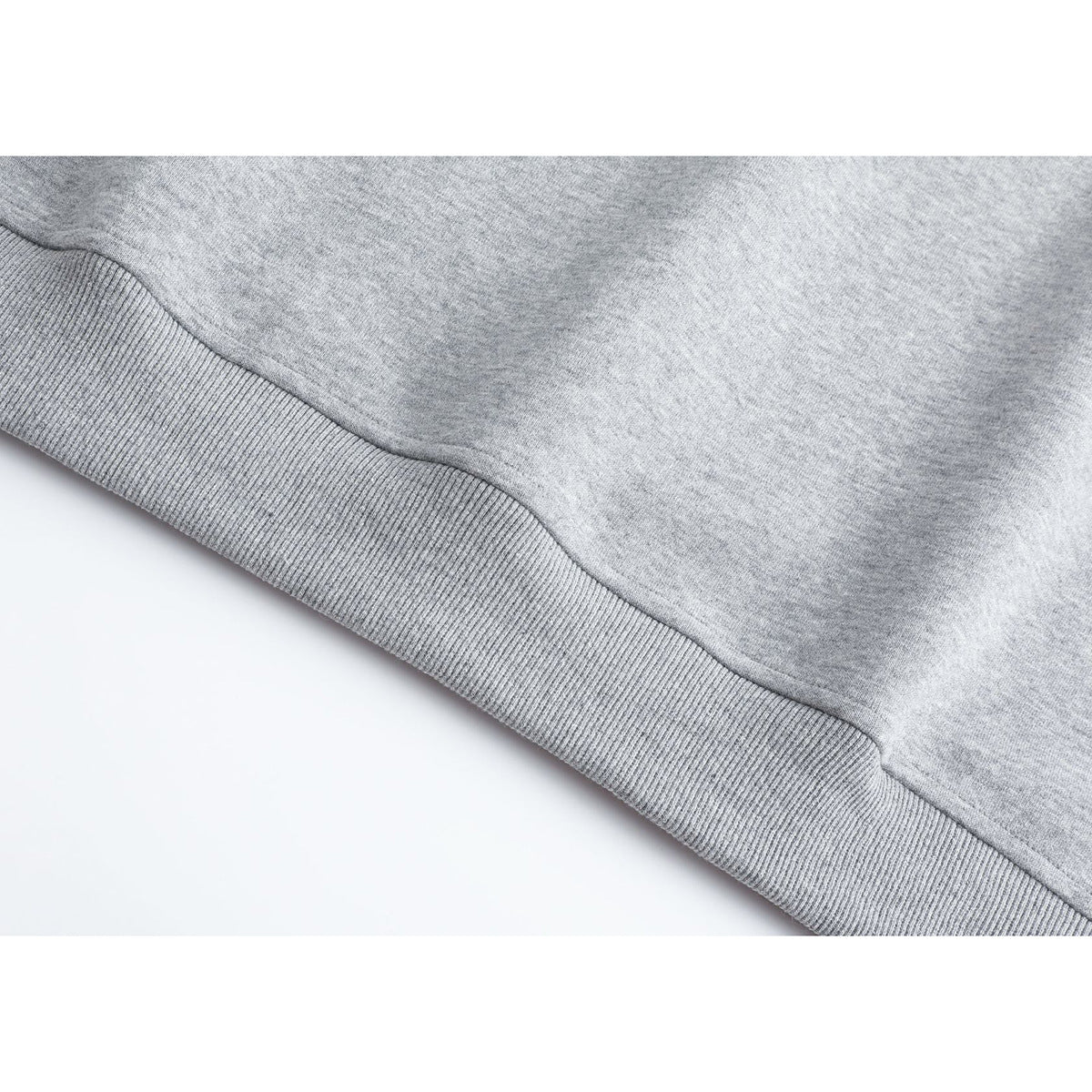 Close-up of the light gray vest's ribbed hem and smooth knit body.