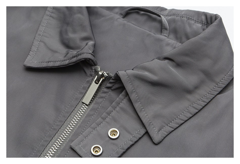 Close-up of a gray jacket collar, silver front zipper and snap-fastened flap.
