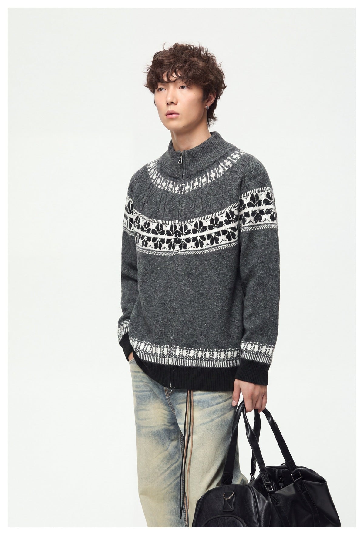 Model wearing a charcoal high-neck knit sweater with a short front zip, cable details and bold white patterned bands.