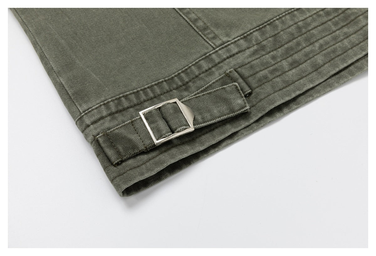 Close-up of an olive-gray jacket hem with a fabric adjustment tab and rectangular metal buckle.