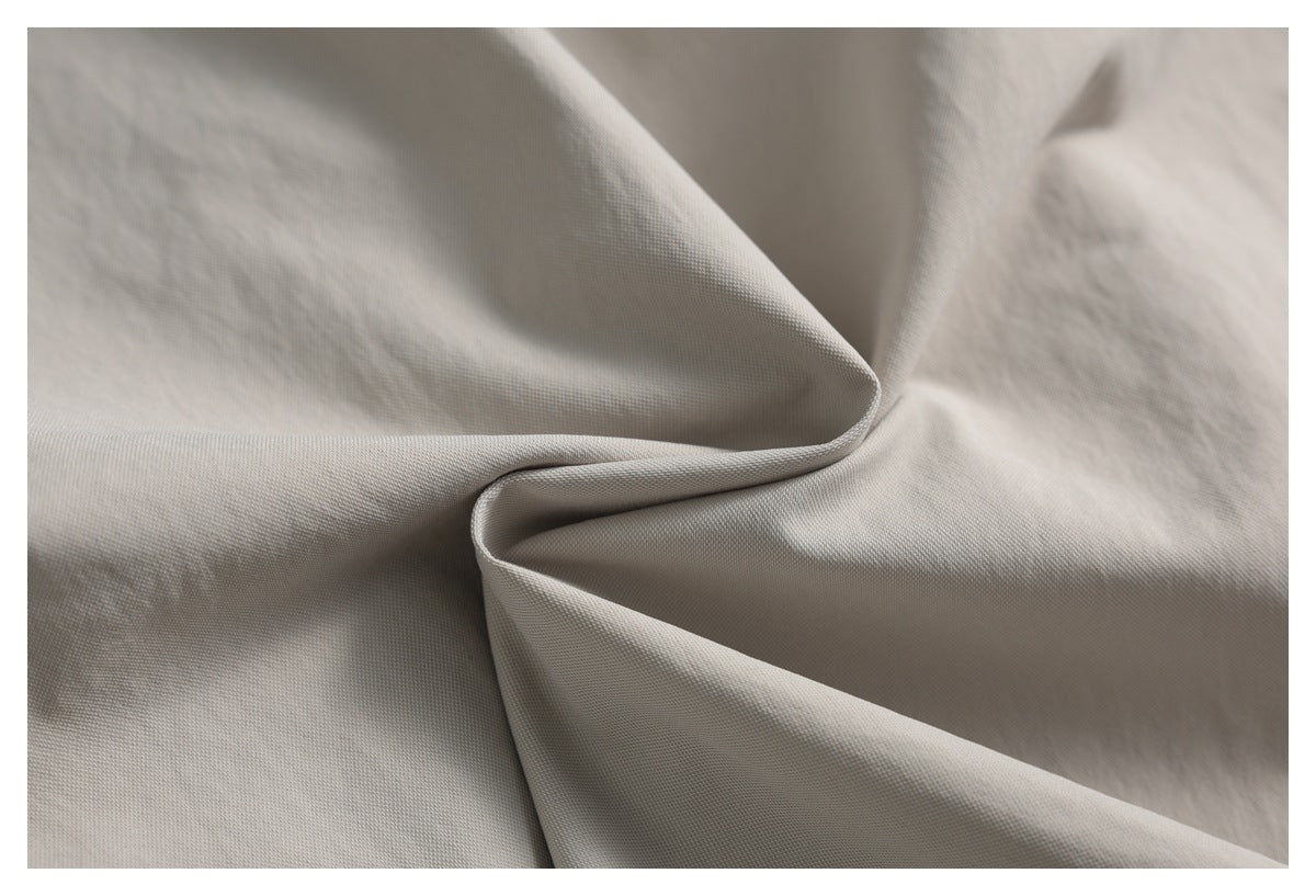 Close-up of light gray-beige woven fabric arranged in soft folds.