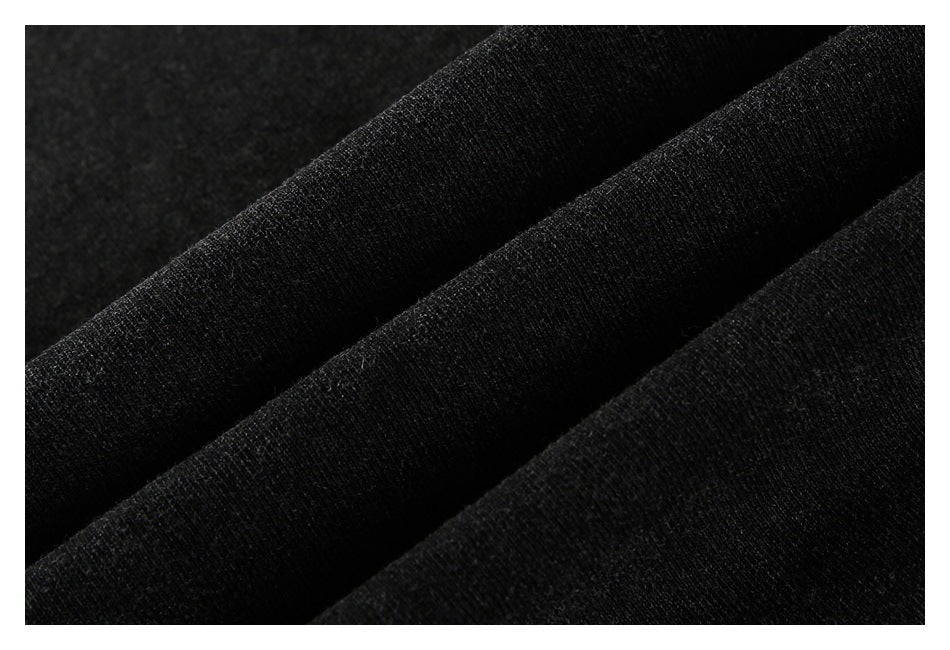 Macro view of black garment fabric arranged in soft folds, showing its fine knit texture.