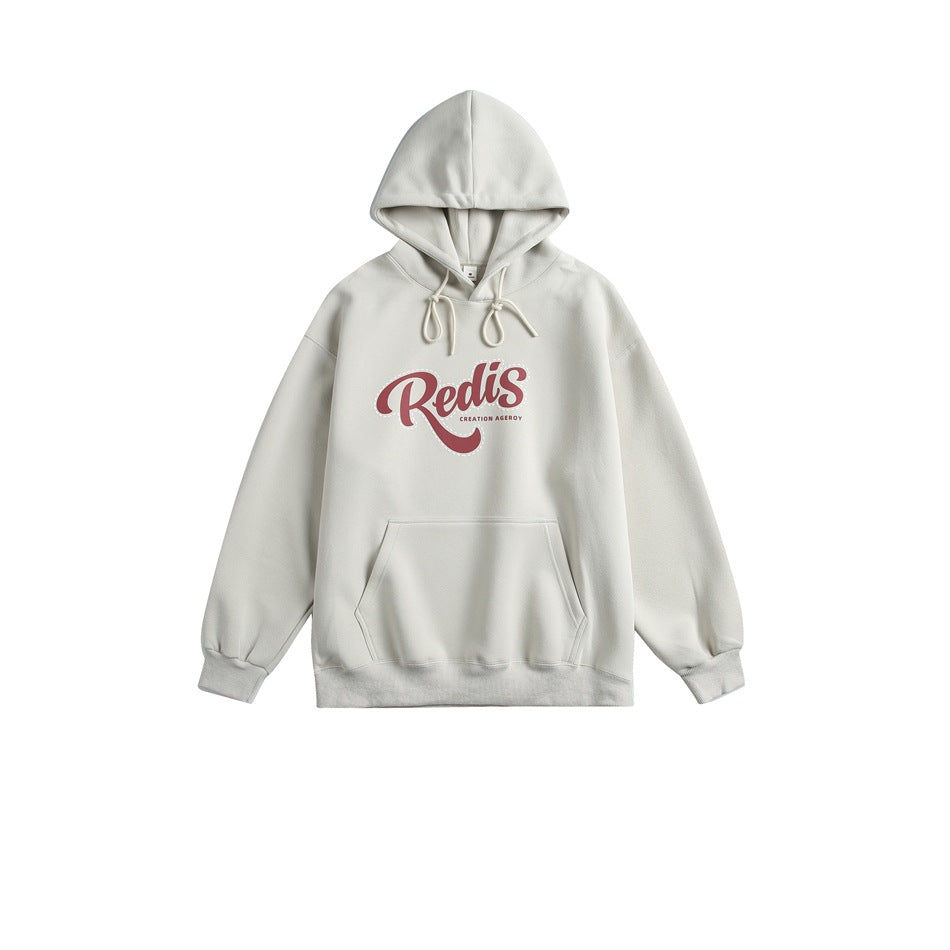 Light apricot pullover hoodie with red script graphic on chest, cream drawstrings and front pocket, flat lay