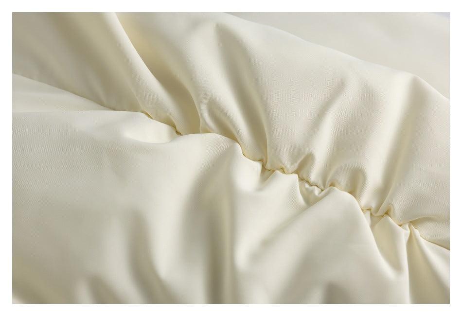 Close-up of ivory fabric gathered along a seam, showing fine surface texture and soft folds.