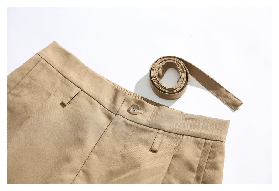 Tan trousers shown at the waistband with a button, belt loops, and a matching rolled belt.