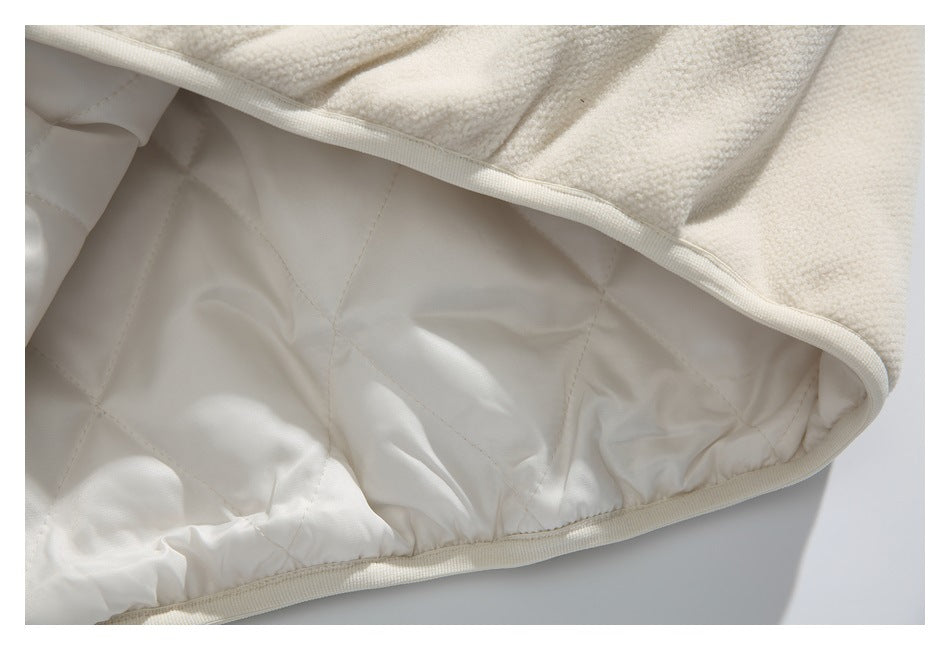 Close-up of ivory garment lining with diamond quilting and bound edge.