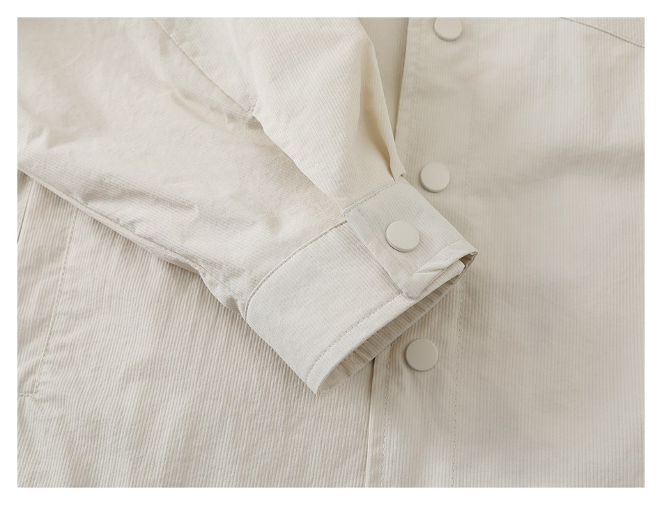Close-up of an ivory ribbed jacket sleeve cuff with large matching buttons and visible stitching.