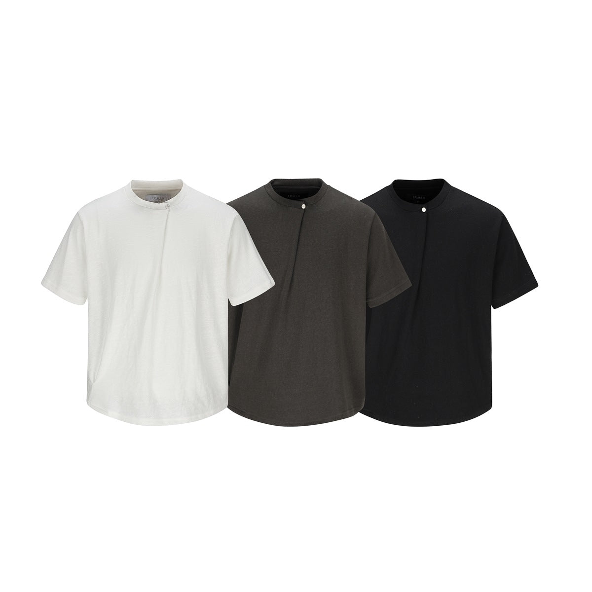 Three short-sleeve tops with round necks and a small button: ivory, charcoal gray, and black, shown from the front.