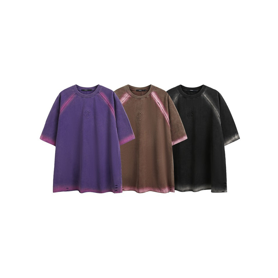 Three oversized T-shirts shown together in purple, brown, and charcoal, each with contrasting faded accents.