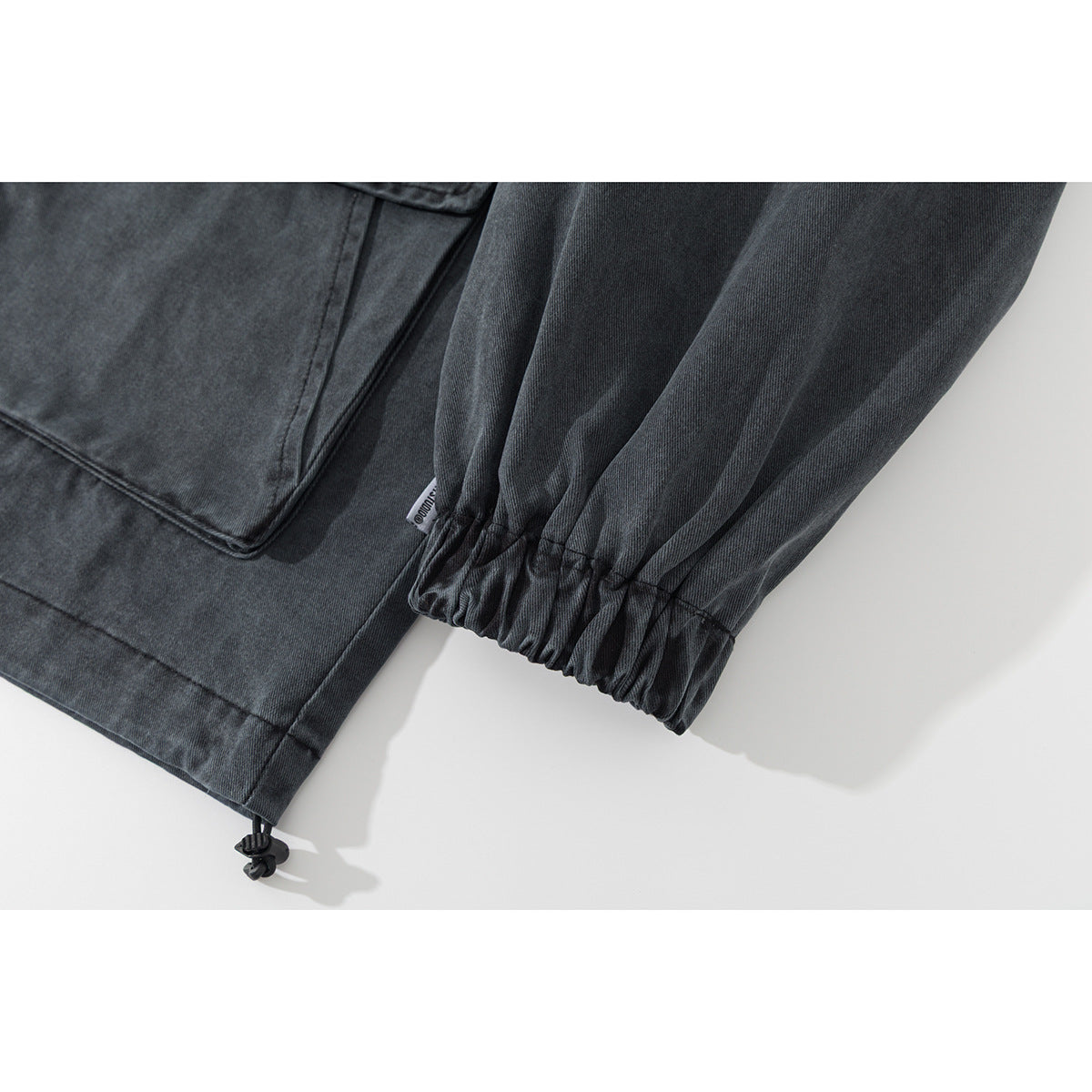 Close-up of the charcoal jacket's elastic sleeve cuff, hem, and adjustable drawcord toggle.