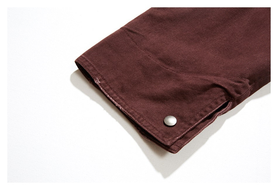 Close-up of a burgundy jacket cuff with a silver snap fastener.