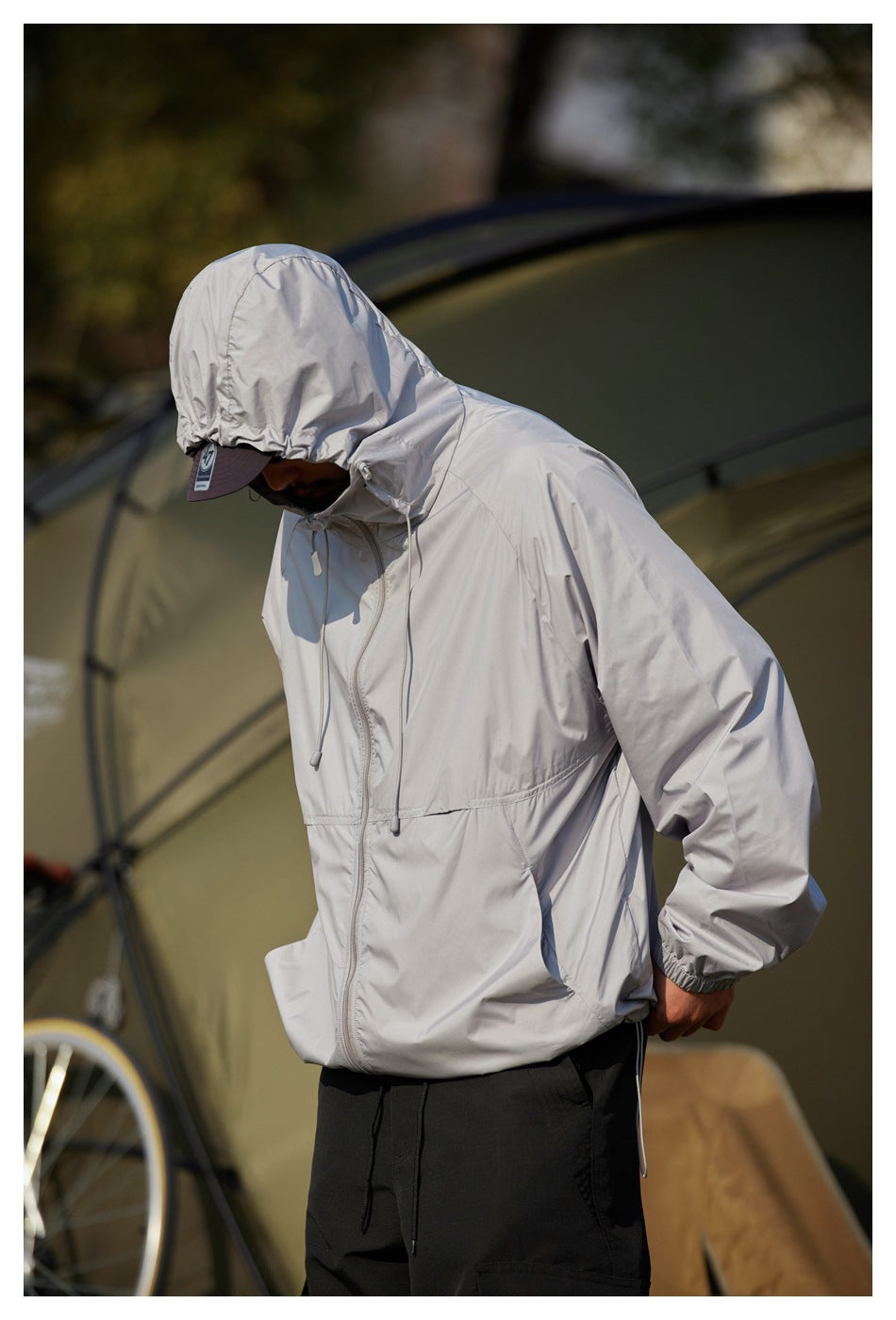 Close view of a model in a light gray hooded jacket with front zipper, drawcords and elastic cuffs.