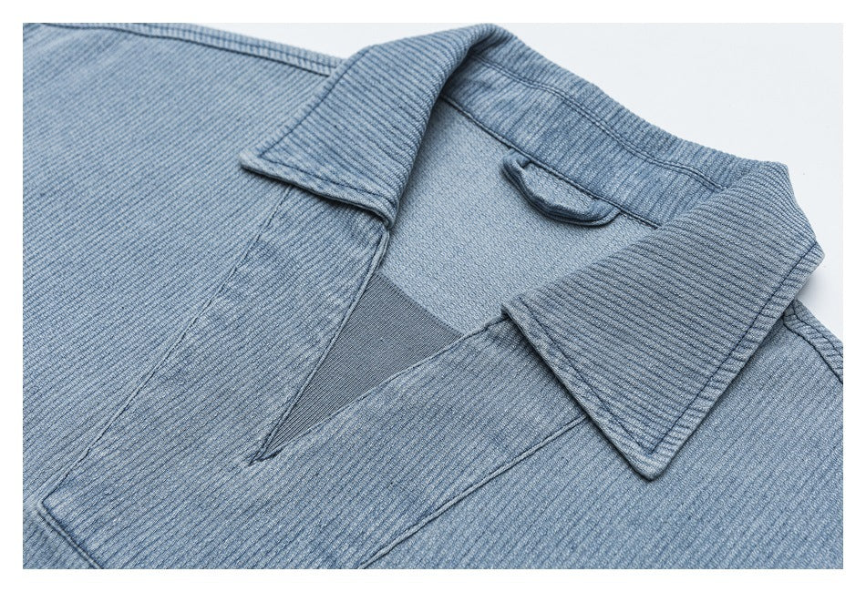 Close-up of a light blue textured jacket showing its pointed collar and front opening.