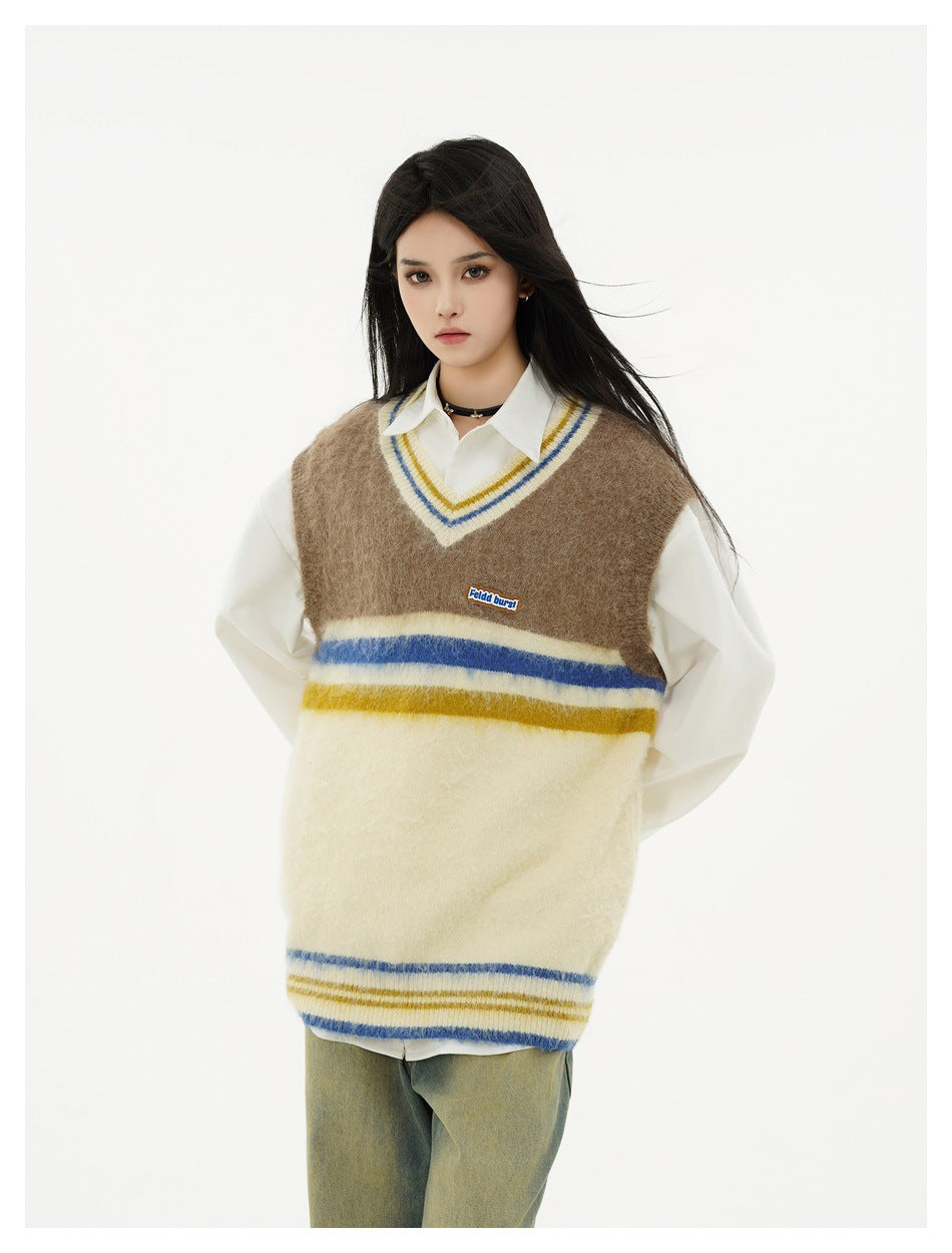 Model in a brown and cream striped V-neck sweater vest layered over a white shirt, hands behind back