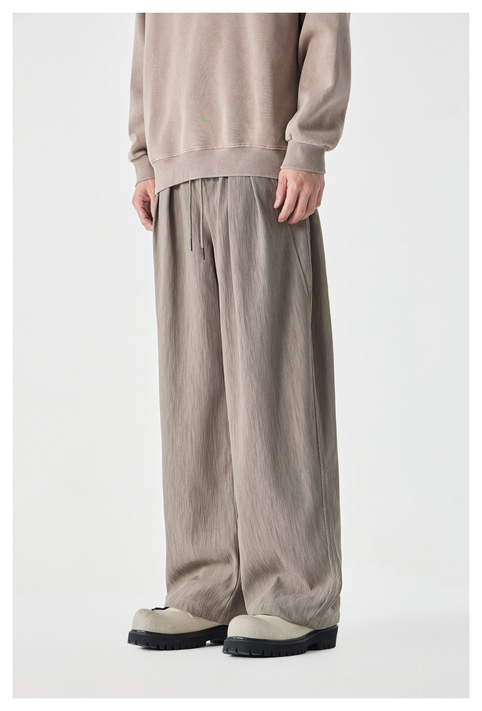 Three-quarter front view of a model wearing taupe-gray wide-leg drawstring pants.