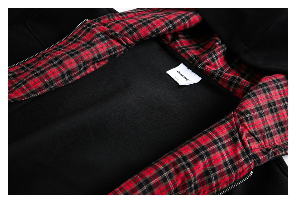 Inside of a black zip-front garment with red plaid lining and a white neck label.