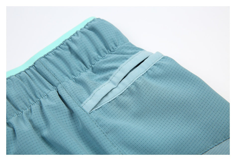 Close-up of blue shorts showing a gathered elastic waistband and a stitched pocket opening.