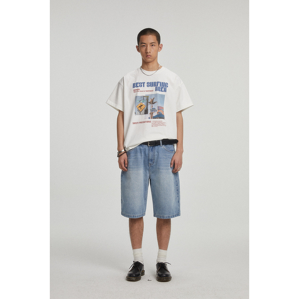 Front view of a model wearing a white graphic T-shirt with light blue denim shorts.