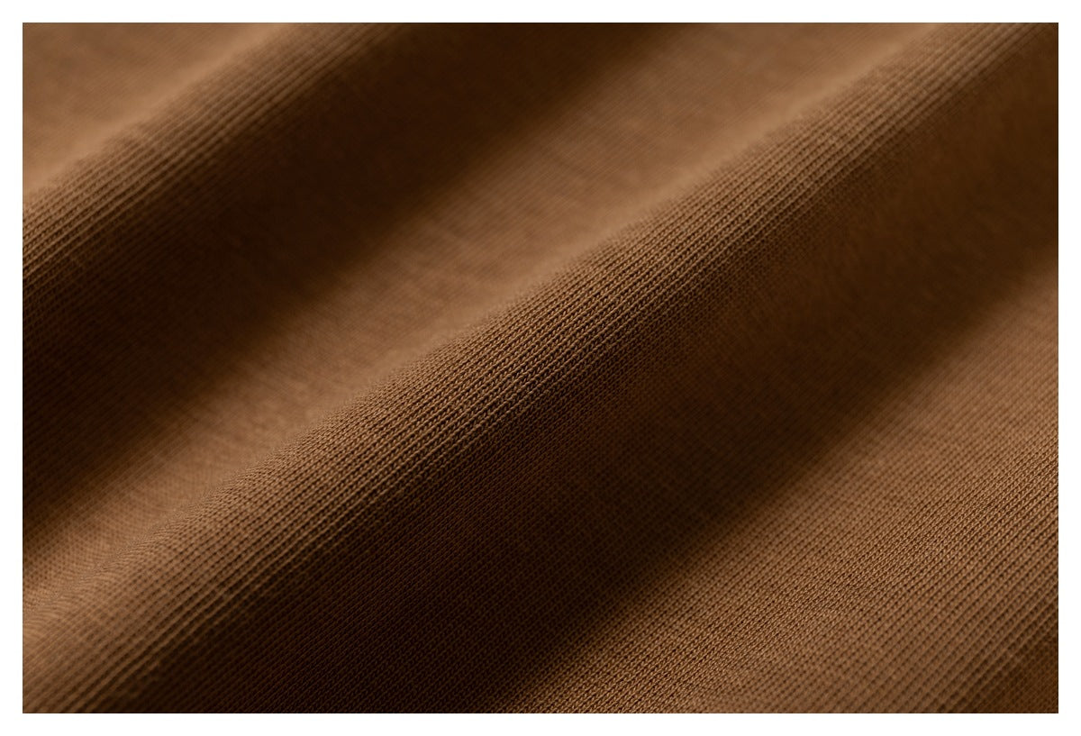 Extreme close-up of brown fabric showing its fine knit texture and soft folds.