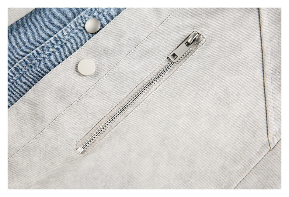 Close-up of a silver zip pocket and white snap button on a light gray jacket with blue denim trim.