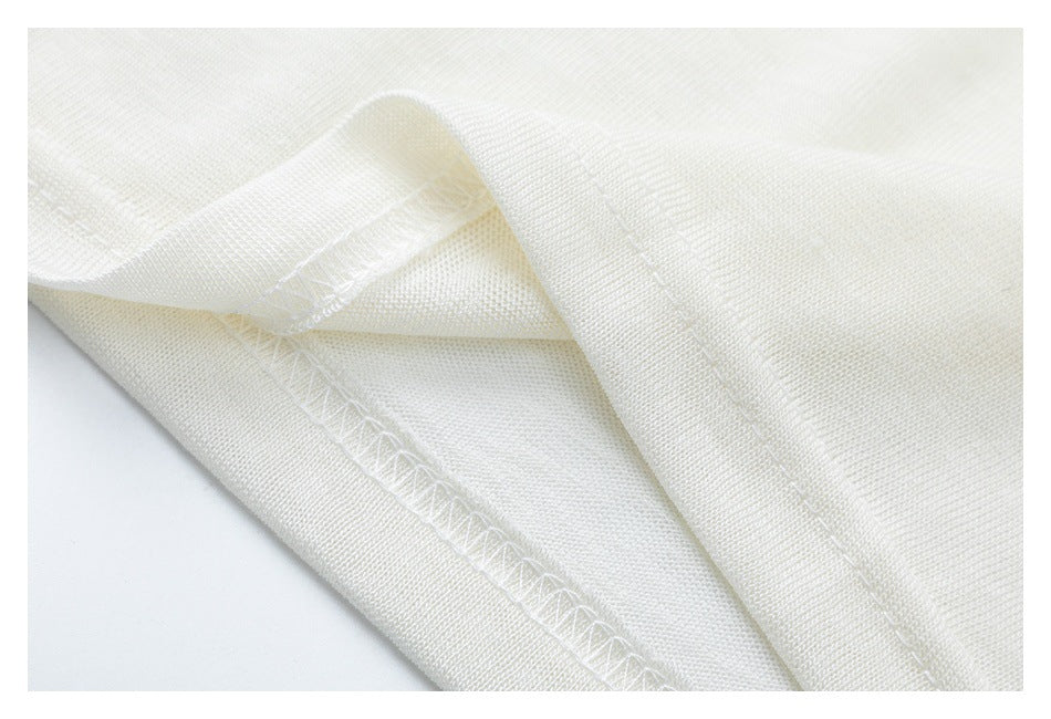 Close-up of ivory fabric with a stitched seam and overlock stitching along a folded edge.