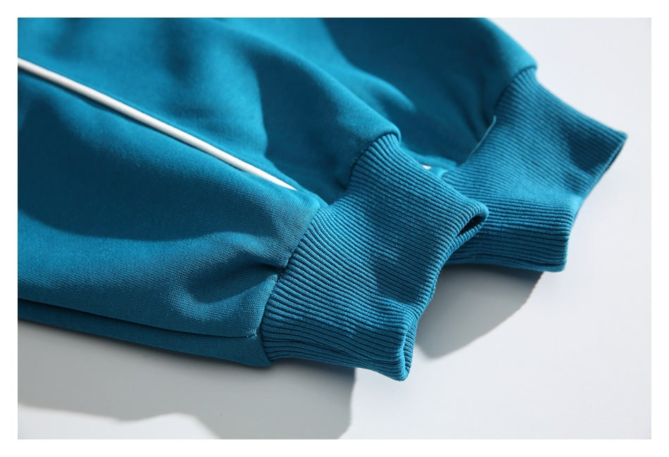 Close-up of the teal garment’s ribbed cuff and white piping.
