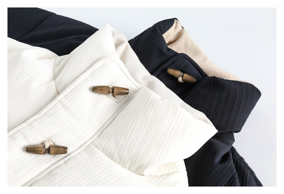 Close-up of ivory and dark navy quilted jackets, showing their collars and wooden toggle fasteners.