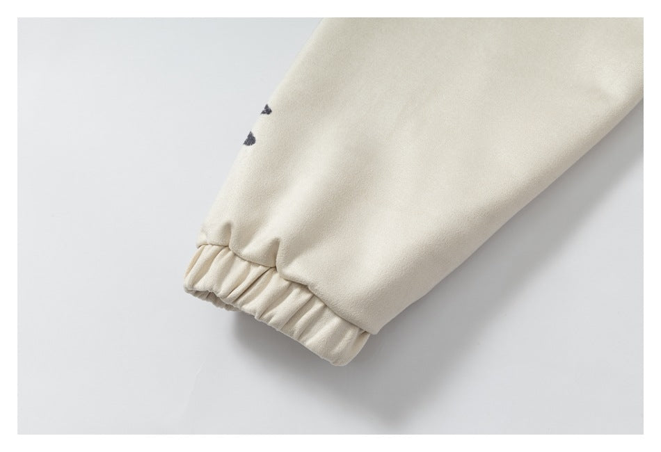 Close-up of an ivory sleeve ending in an elasticized cuff, with small black print marks.