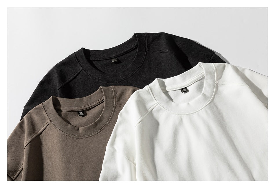 Three plain crewneck sweatshirts in black, taupe, and white, overlapping in a close-up view.