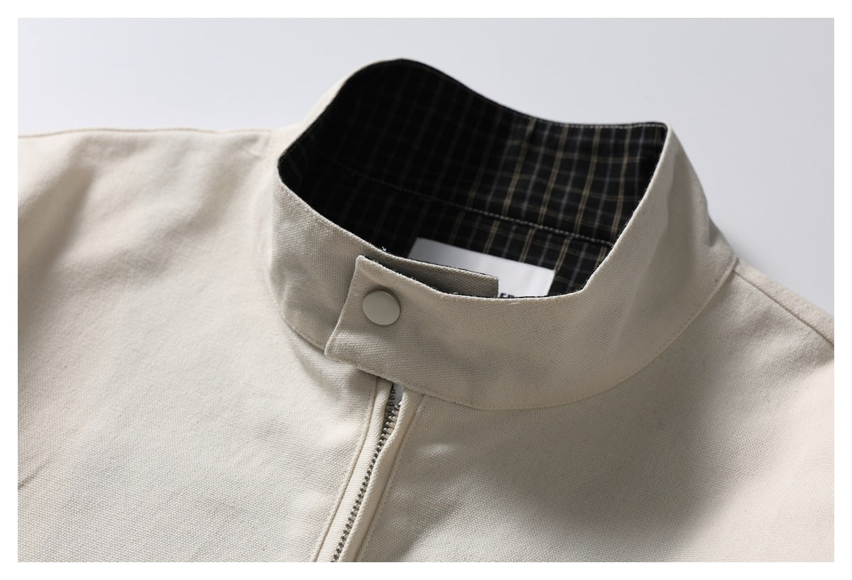 Close-up of the ivory stand collar with a snap closure, zipper and black plaid inner collar.