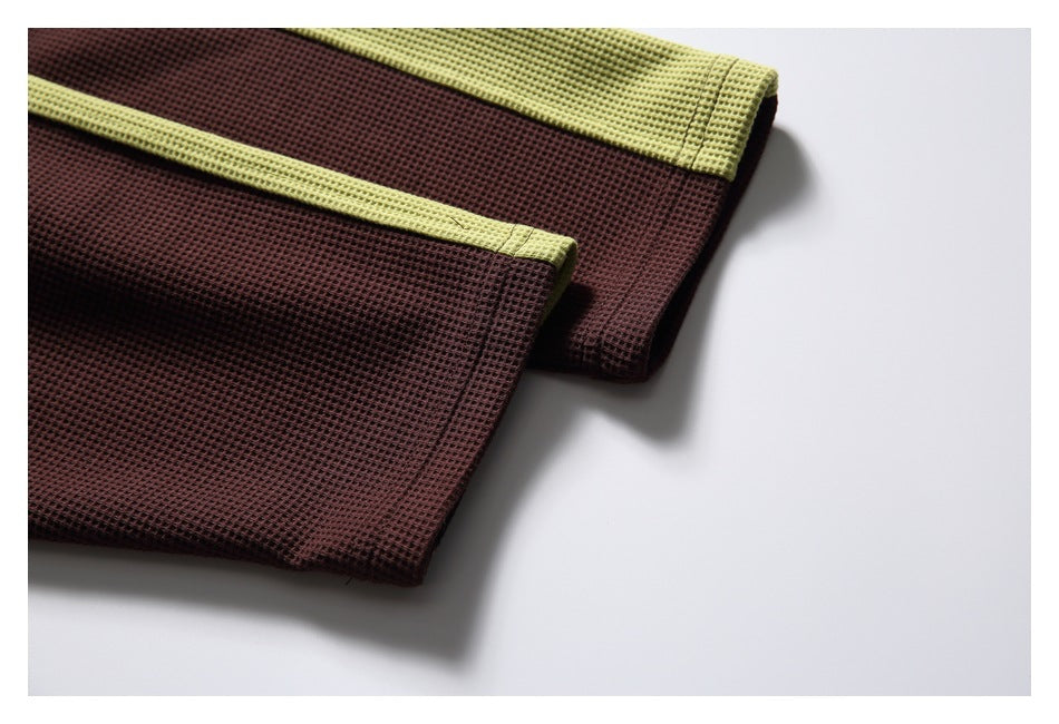 Close-up of the burgundy waffle-knit garment hem with a narrow chartreuse contrast edge.