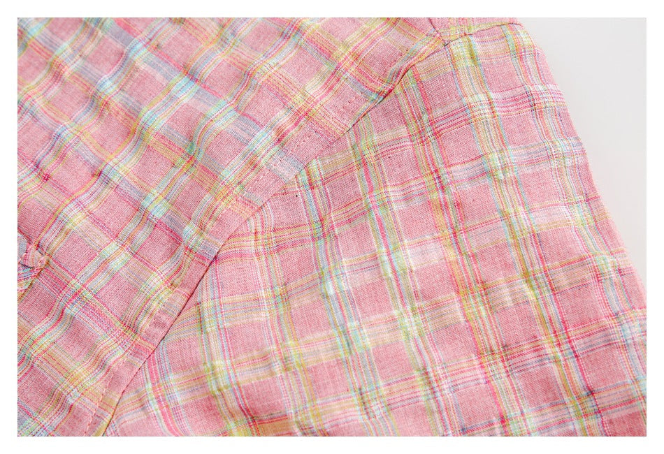 Close-up of pink plaid garment fabric with intersecting pastel stripes and a curved seam.