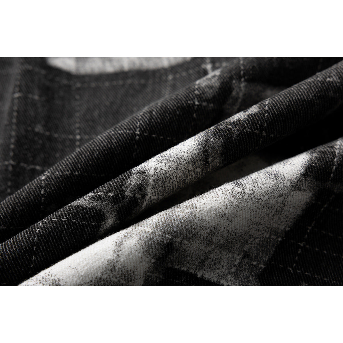 Extreme close-up of the jacket's dark gray and white patterned textile and diagonal folds.