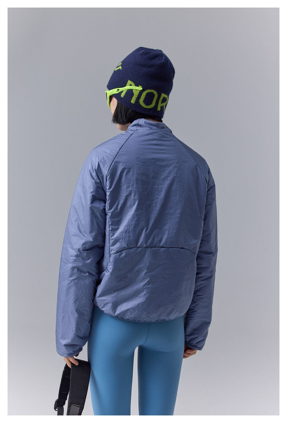 Rear view of a model wearing a periwinkle-blue padded jacket and blue leggings.
