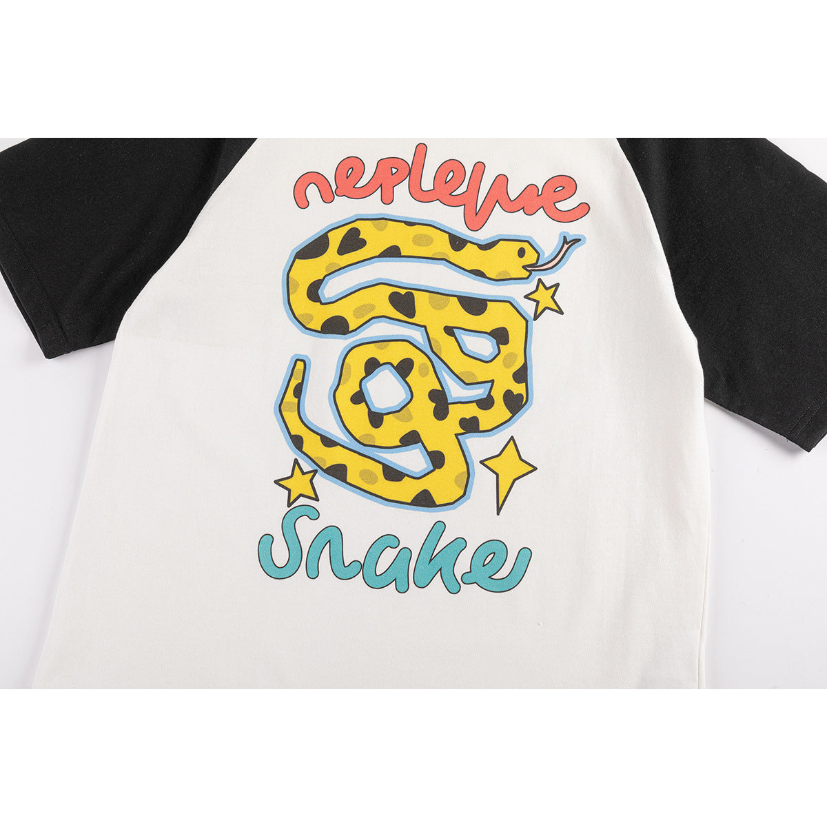 Close view of an off-white raglan T-shirt with black sleeves and a colorful yellow snake-and-star graphic.