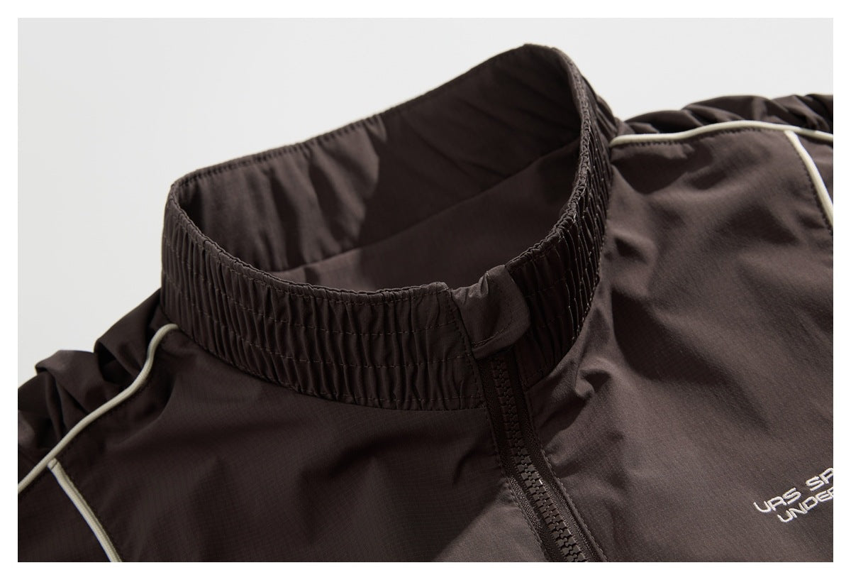 Close-up of a dark brown jacket's gathered stand collar, front zipper, and light piping.