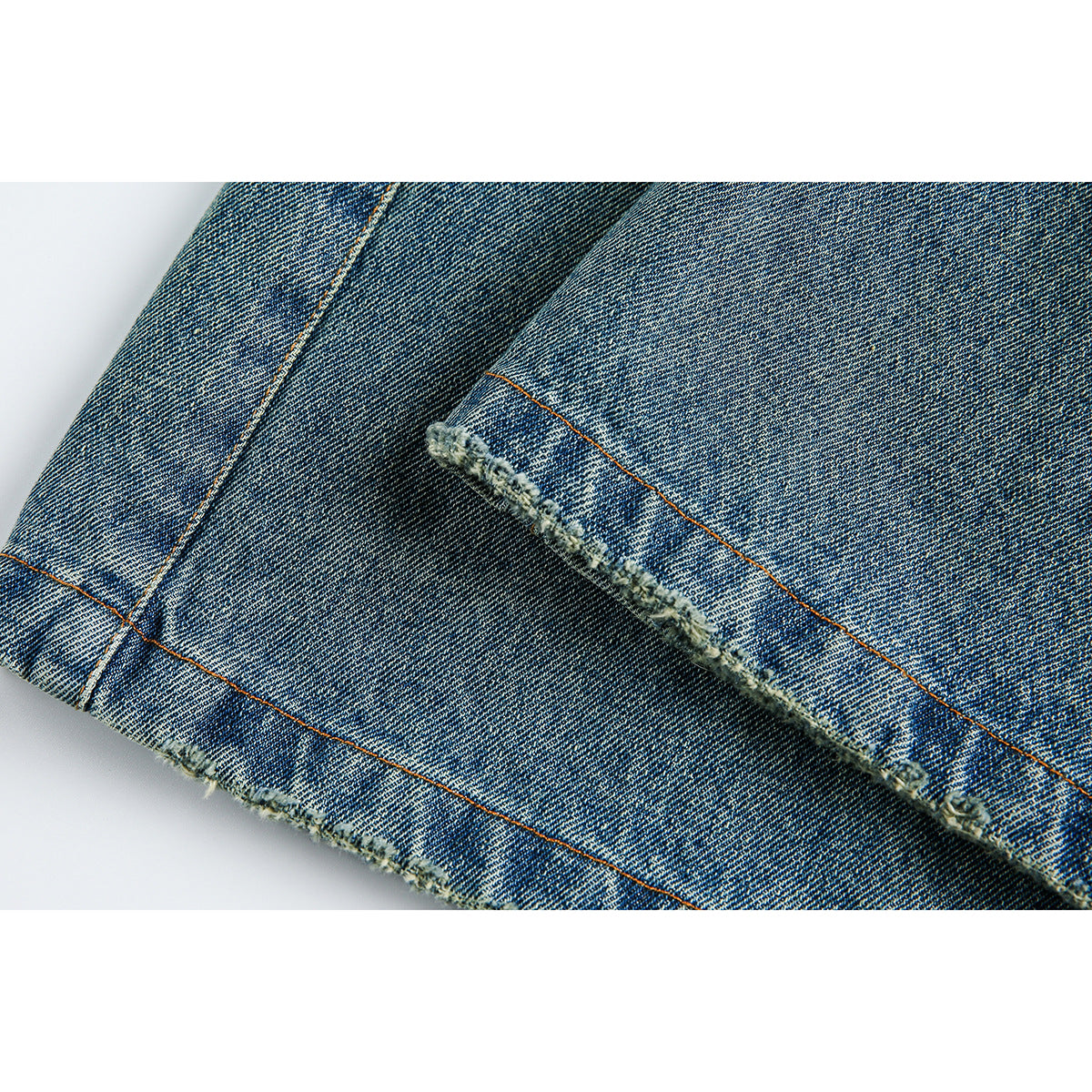 Close-up of faded blue denim shorts showing a raw, frayed hem and orange topstitching.