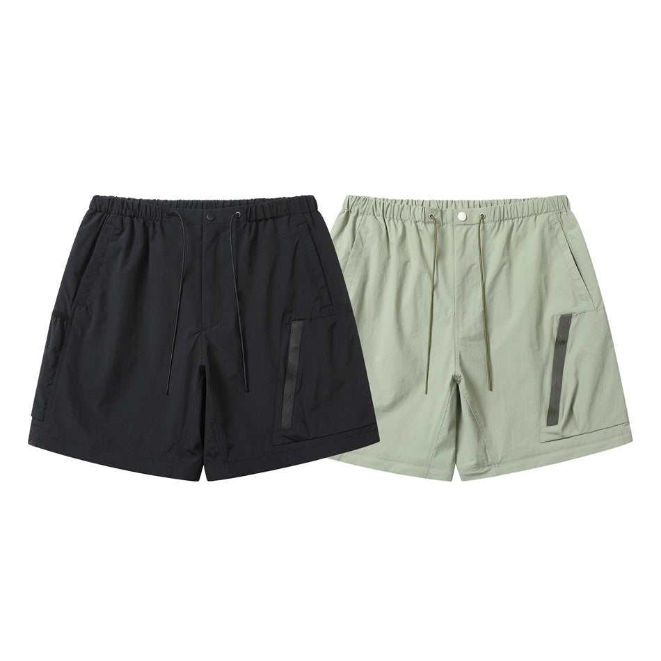 Front view of black and pale sage-green cargo shorts with elastic drawcord waists and dark-trimmed pockets.