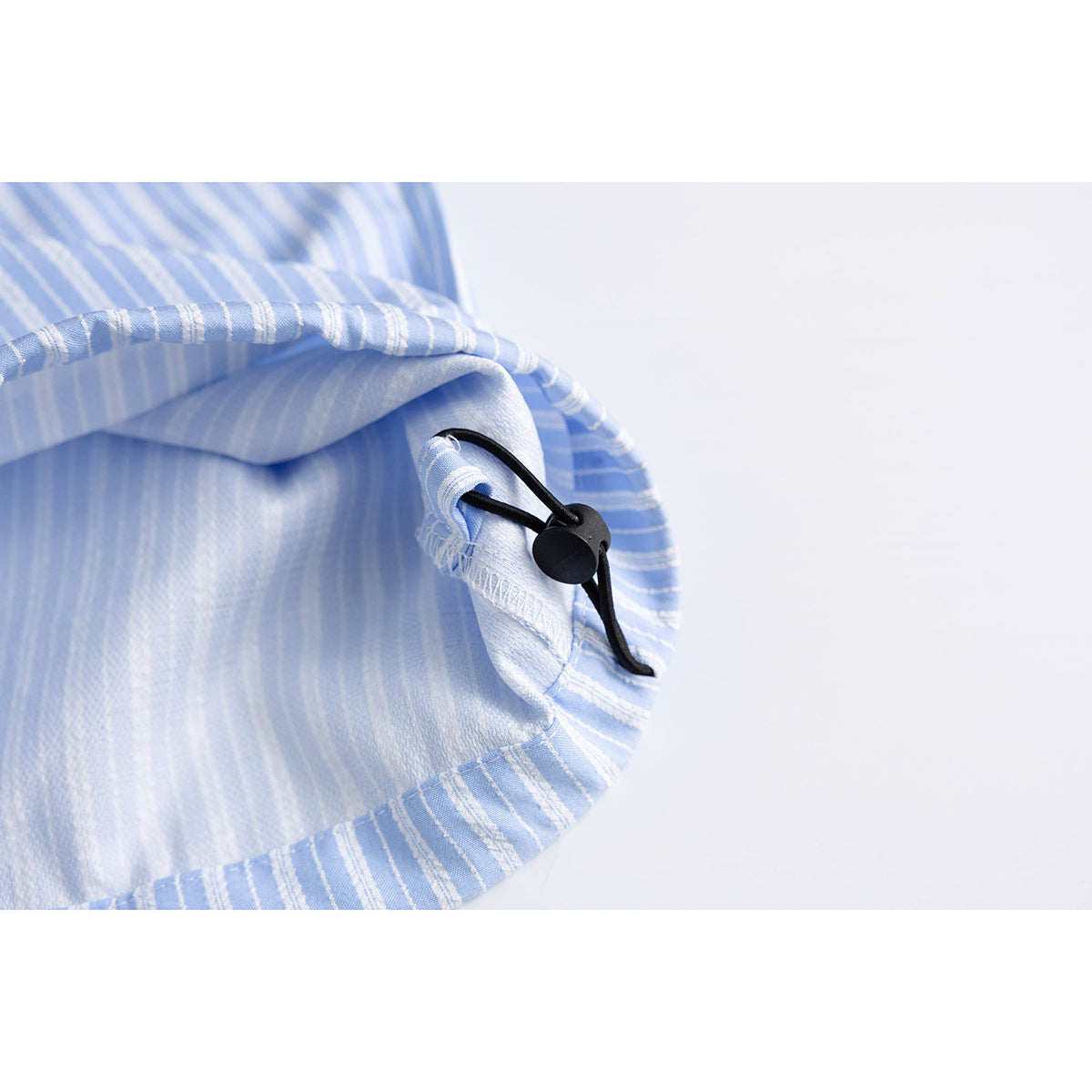 Close-up of the inside hem of light blue striped shorts, showing a black adjustable cord and stopper.