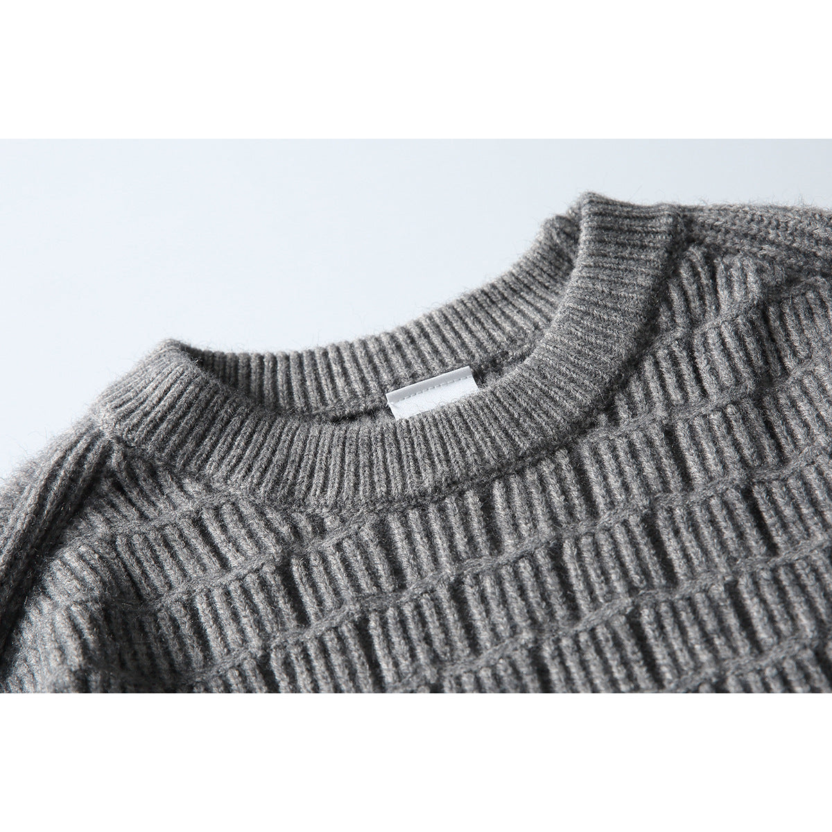 Close-up of a gray knit sweater's ribbed crew neck and textured stitch pattern.